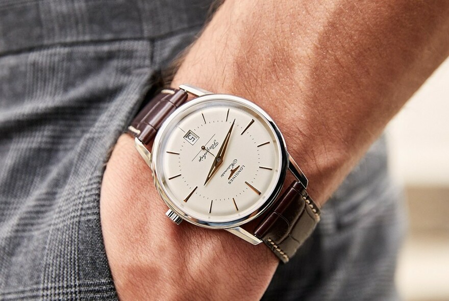 Close-up of male model's hand wearing a wristwatch with his hand in his pocket.