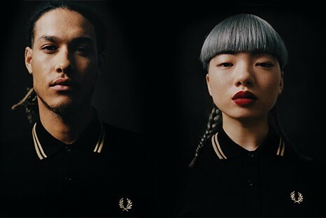 Two darkly shot male and female models wearing Fred Perry logo polos.