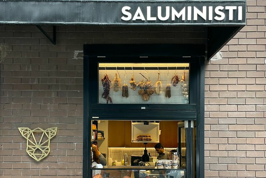 A view of the restaurant Saluministi through a black-framed window in a brown brick wall.