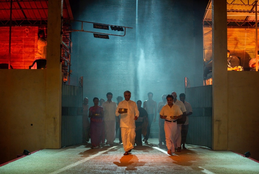 A group of people walking through blue smoke onto a stage.