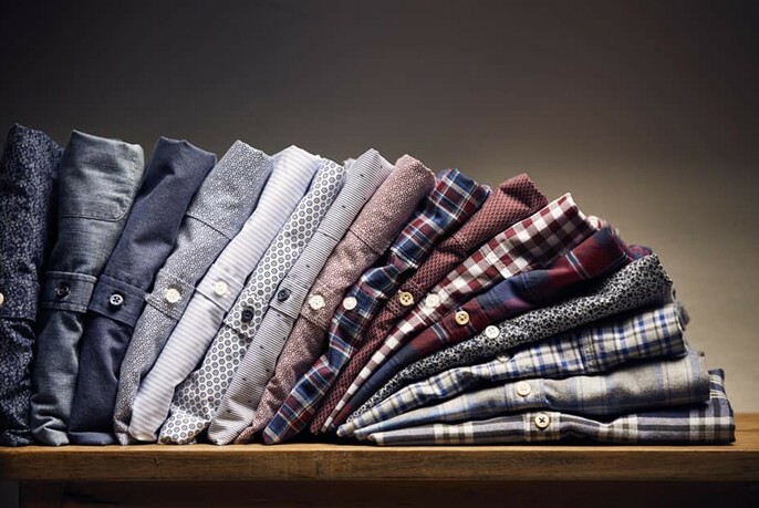 Row of folded men's shirts, collapsing from left to right.