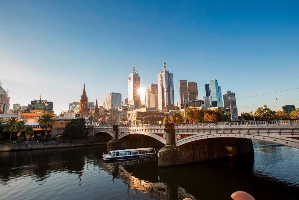A boat cruising down the Yarra River at sunset with the city skyline in view.
