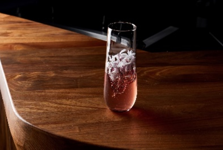 Pink cocktail with white garnish.