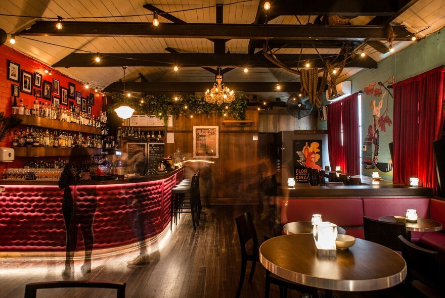 Interior of Murmur featuring red padded curved bar, wooden floor, tables and lounge booth areas.