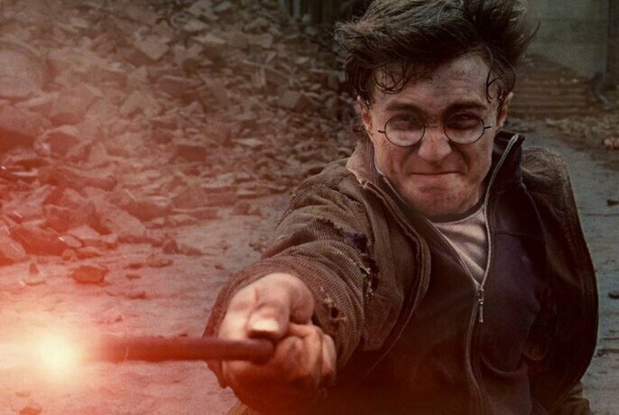 Movie still of Harry Potter waving an illuminated wand.