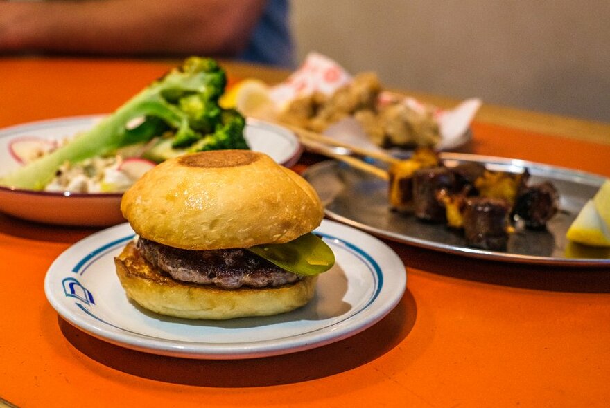 An orange table set with a burger and other dishes.