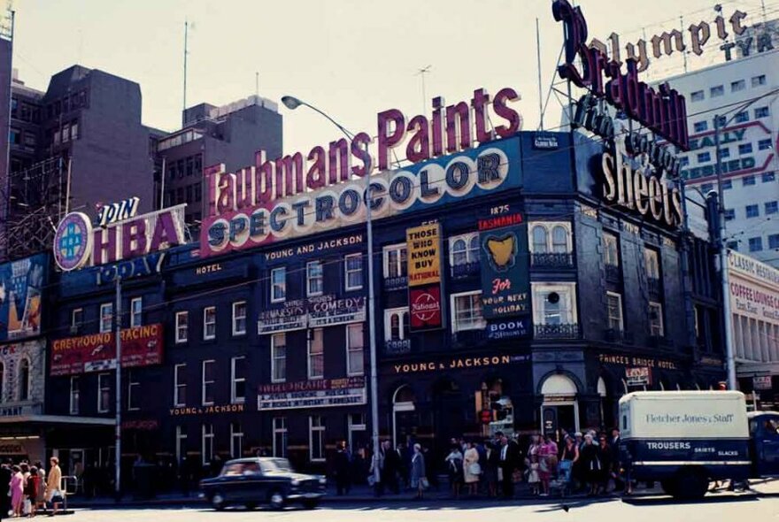 An old photo of a corner pub with large advertising signs.