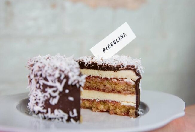 A lamington-flavoured layered gelato cake on a plate with a slice taken out. 