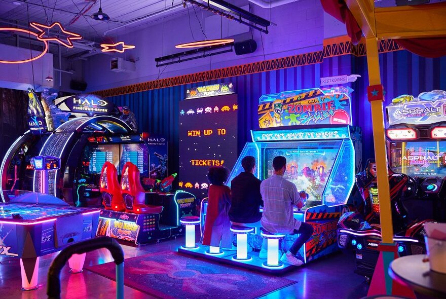 Three friends playing an arcade game.