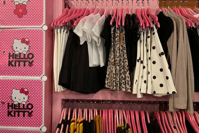 Pink Hello Kitty lockers next to racks of clothing.