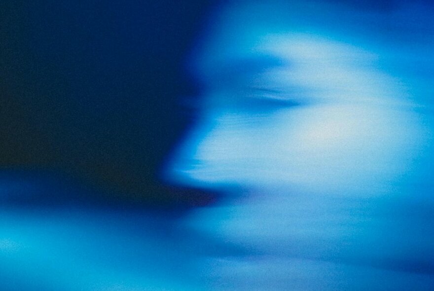 A blurred motion close-up of a person's face with a blue cast over the top of the image. 