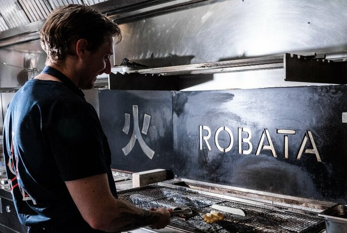 Chef Stephen Clark working at a grill with Robata branding.