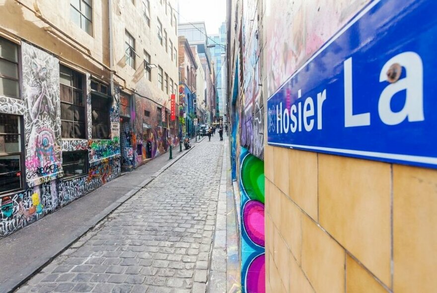 Hosier Lane sign with view of cobbled and graffitied laneway.