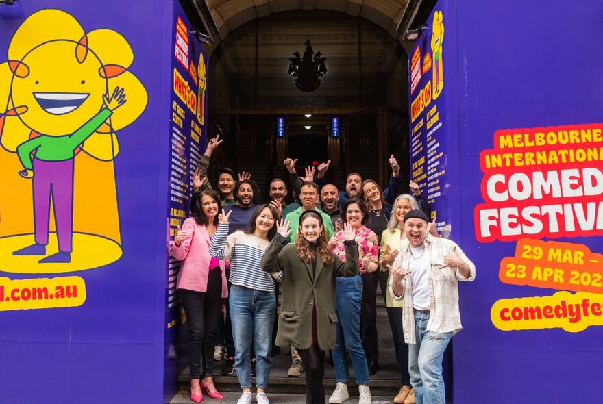 A group of people standing in the entrance of the Melbourne Town Hall with Melbourne International Comedy Festival signage on either side.