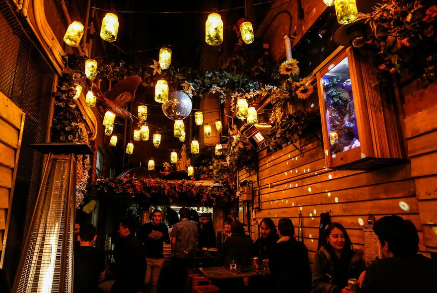 Small outdoor bar in a laneway at night with hanging lanterns.