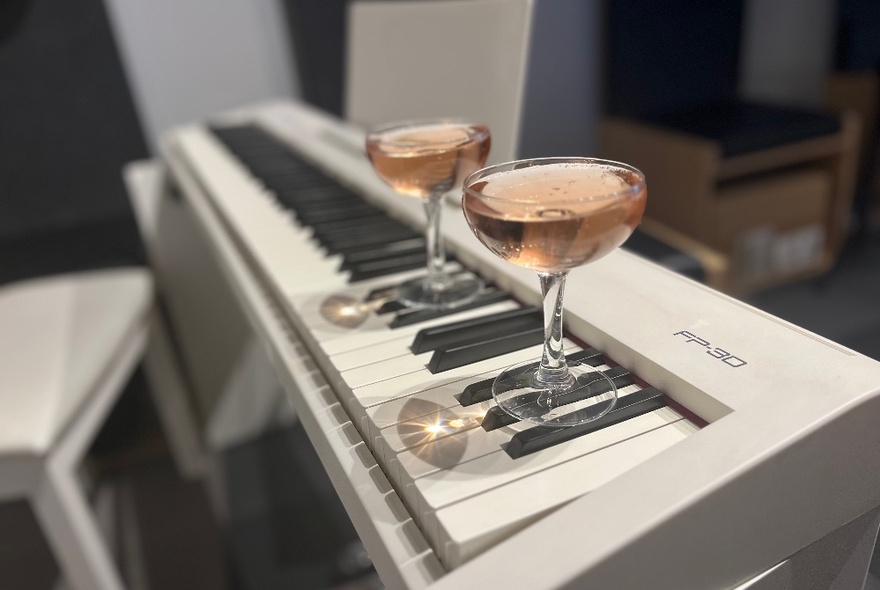 Two glasses of wine balancing on top of a small beige electronic keyboard.