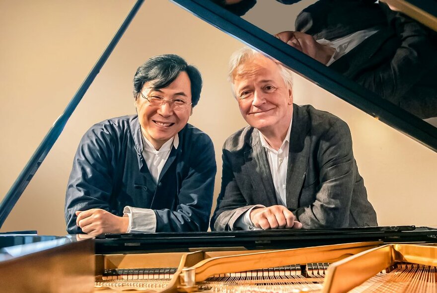 Chinese baritone Liao Changyong and German pianist Hartmut Höll leaning into the open lid of a grand piano.