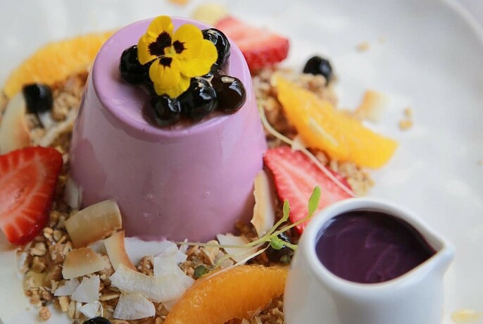 Purple dessert served with fruit and chocolate sauce. 