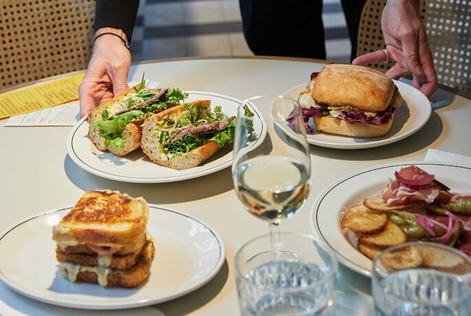 Plates of sandwiches and a glass of wine in a cafe.