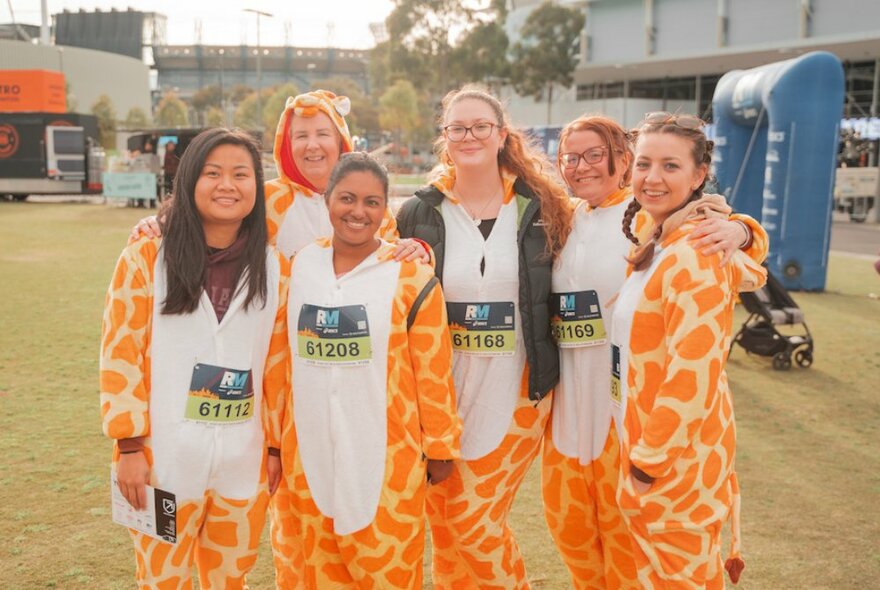Six people dressed in giraffe onesies, about to take part in a fun run.