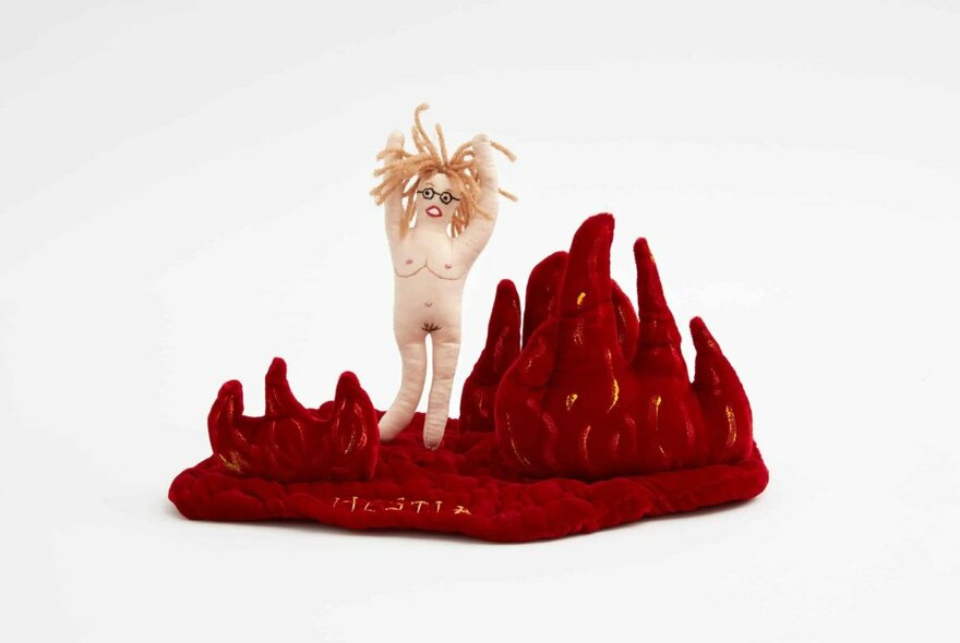 A small sculpture of a naked wild-haired woman in red grass or coral. 