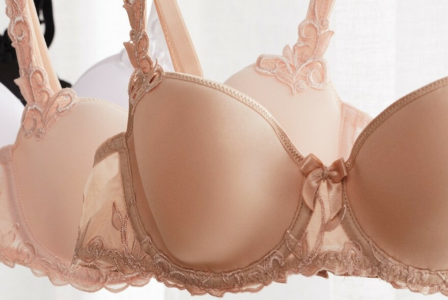 Beige, pink and white bras with lace edging  hanging.