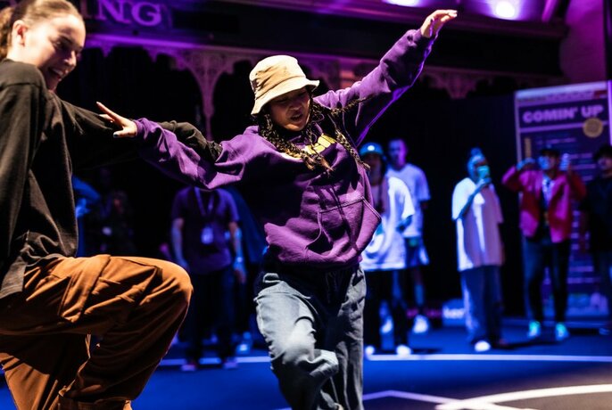 Dancers wearing rap hats and clothing performing in front of people.