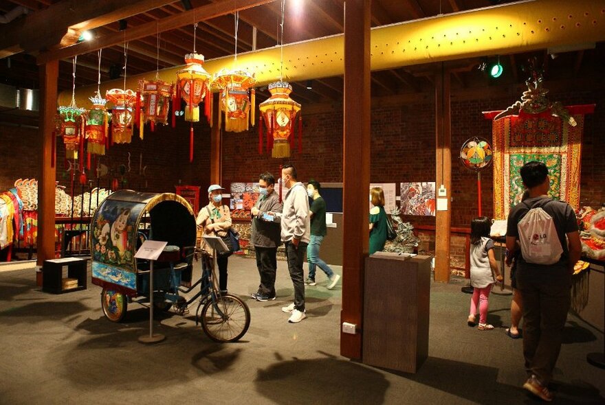 People browsing a museum with paper lanterns and artwork. 
