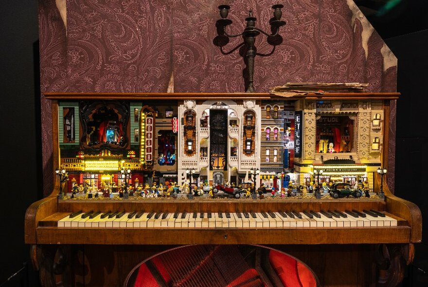 Upright piano, with a tableau featuring LEGO figures inside.