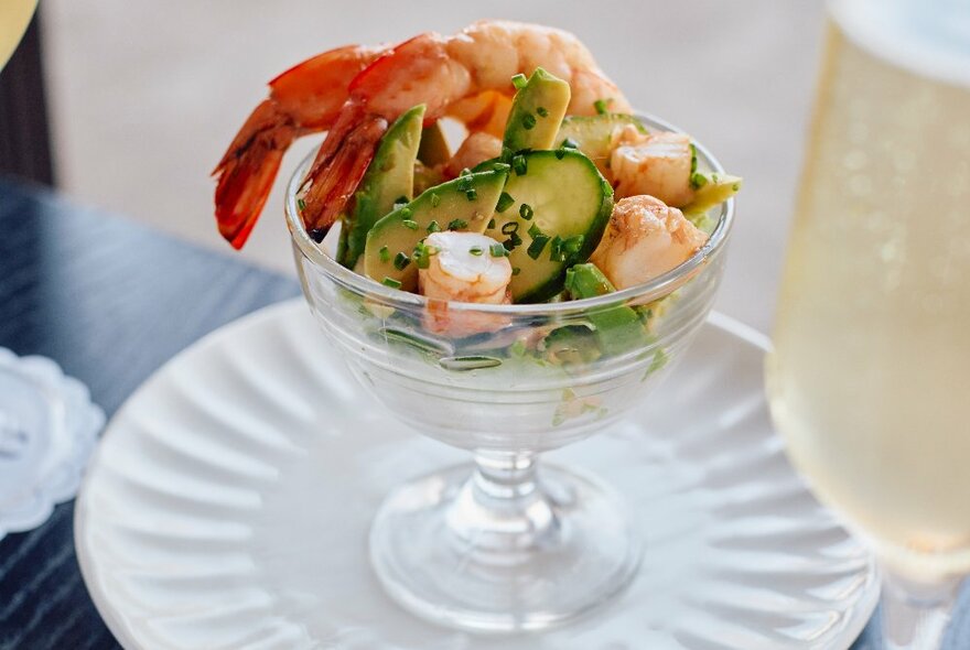 A prawn cocktail with an out of focus glass of champagne. 
