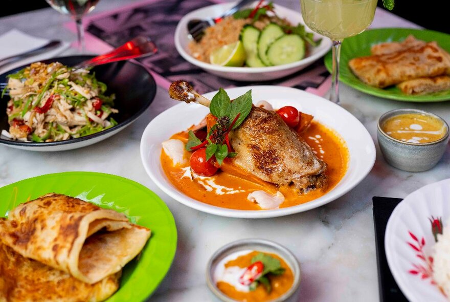 A selection of delicious Thai-style dishes on a marble table.