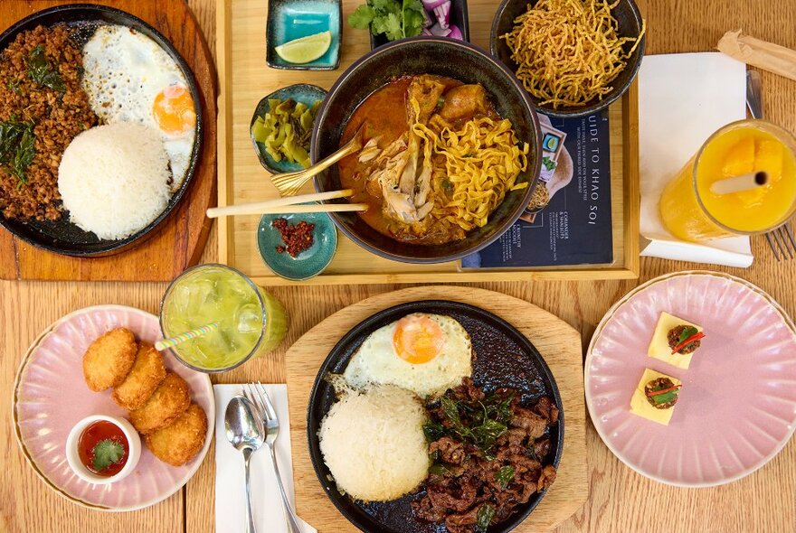 A selection of Thai dishes and drinks on colourful plates.