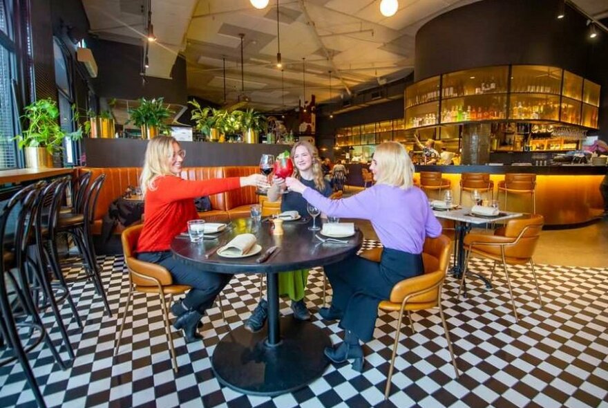 Three women saying cheers at a table