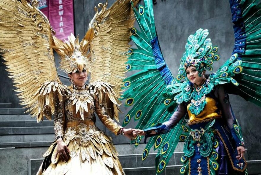 Indonesian dancers wearing elaborate feathered gowns with matching wings and headdresses.