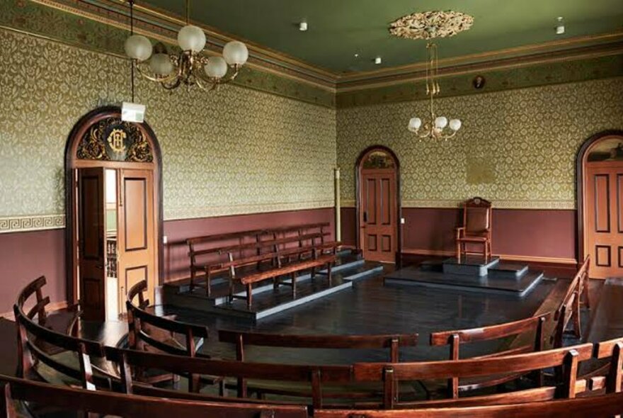 Trades Hall Chamber with vintage decor of wallpaper and lighting, with circular seating.