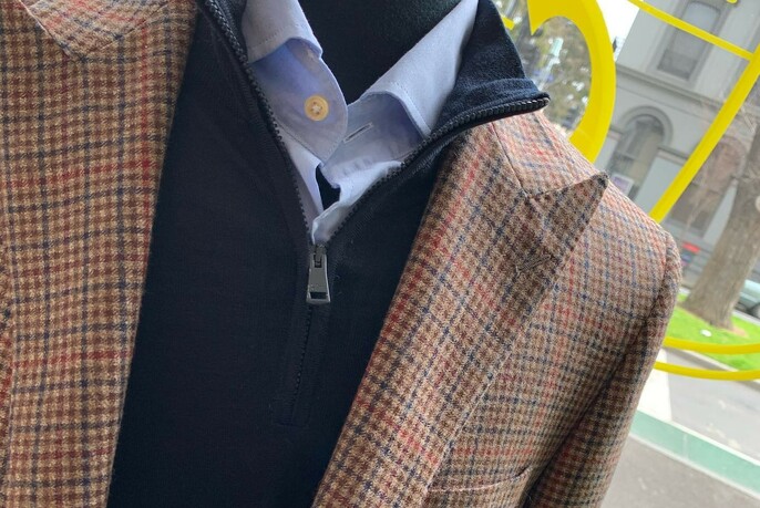 Houndstooth jacket with zippered jumper and blue shirt underneath.
