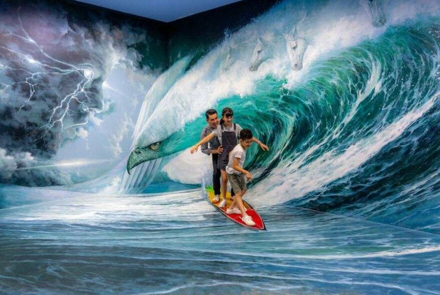 A family of three standing in front of a painting that looks like a wave