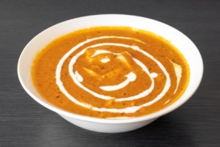 White bowl of dahl, with white sauce drizzled at top.