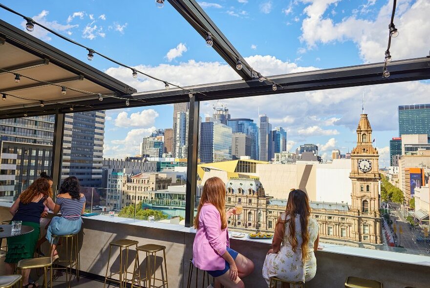 People looking at a view of Melbourne GPO from a rooftop bar on a sunny day.