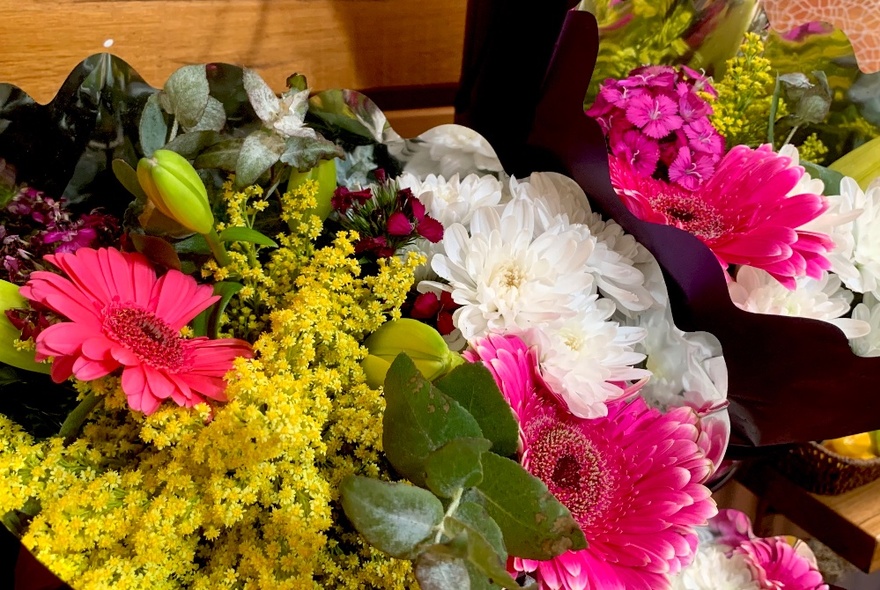 Assorted flowers on display including pink and white gerberas and yellow wattle.