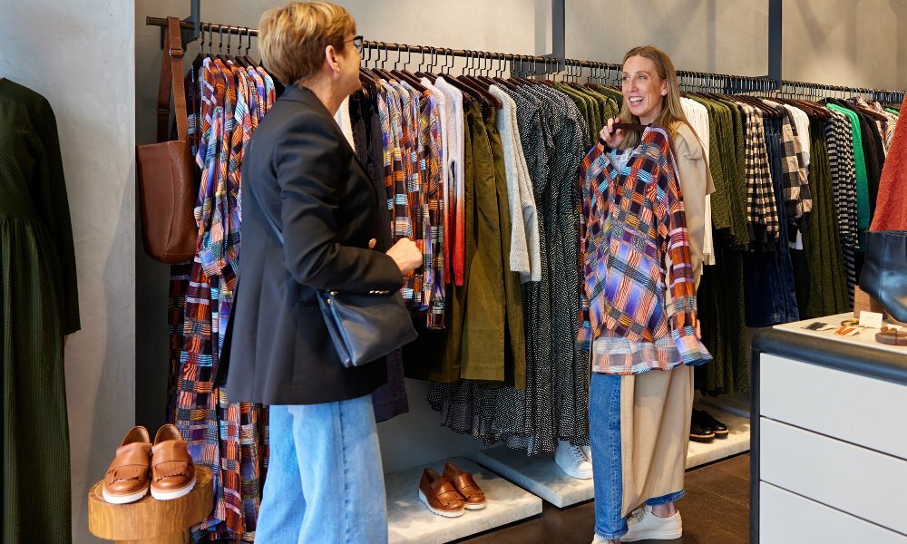 Two women are browsing clothes in a clothing store