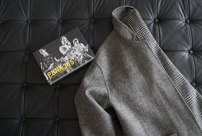 A stylish grey blazer with a tag, folded and lying on a couch. 