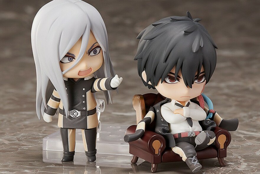 Two anime figurines, one seated in an armchair.
