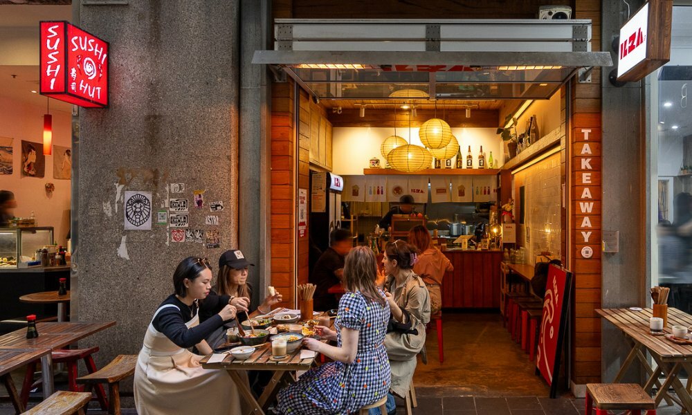 A group dining outside a tiny glowing laneway cafe.