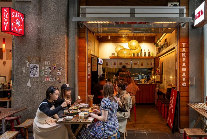 A group dining outside a tiny glowing laneway cafe.
