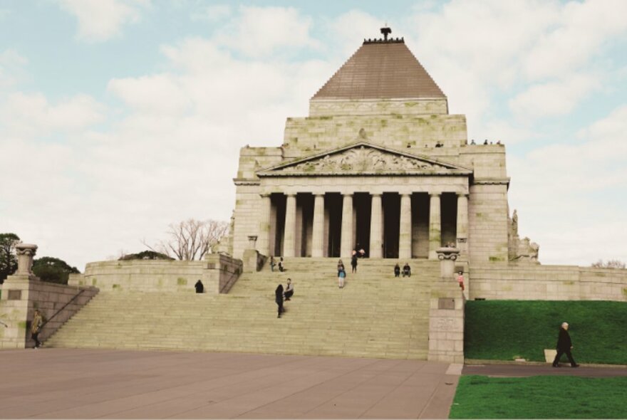 The Shrine of Remembrance building, a large concrete building with a classical portico and facade and steps leading up to it.