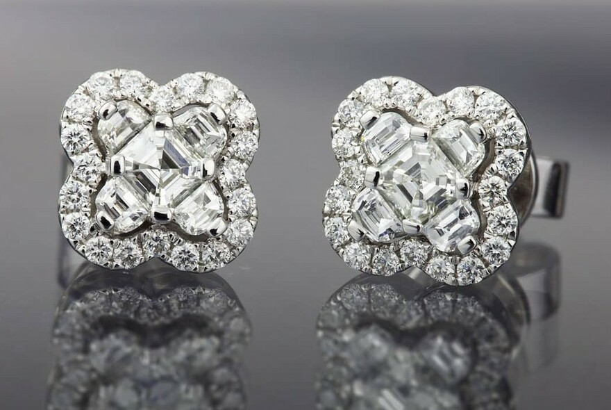 Two diamond earrings on a grey background.