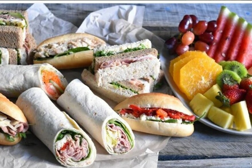 Selection of rolls, sandwiches, wraps and fruit.