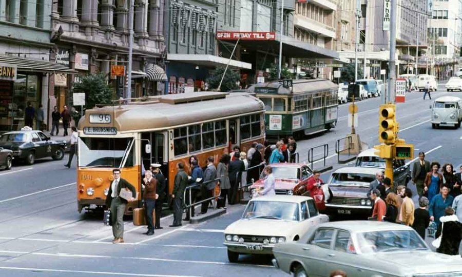 An old photo of a yellow tram on a city street