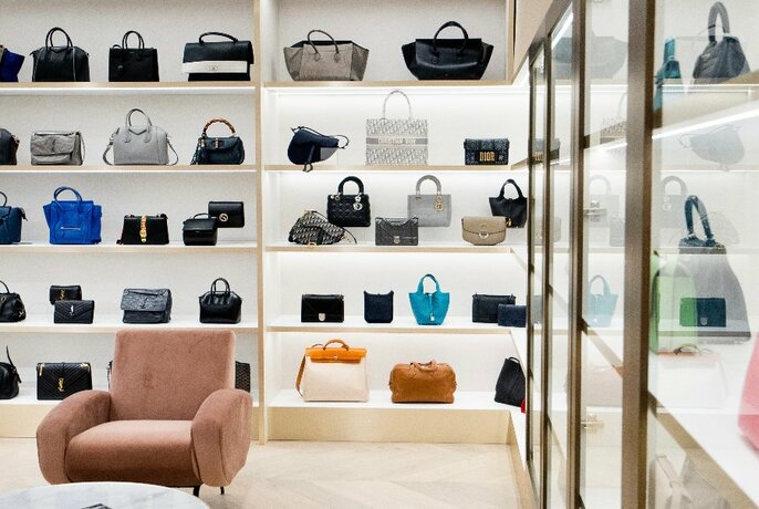Store shelving units filled with multicoloured designer handbags.